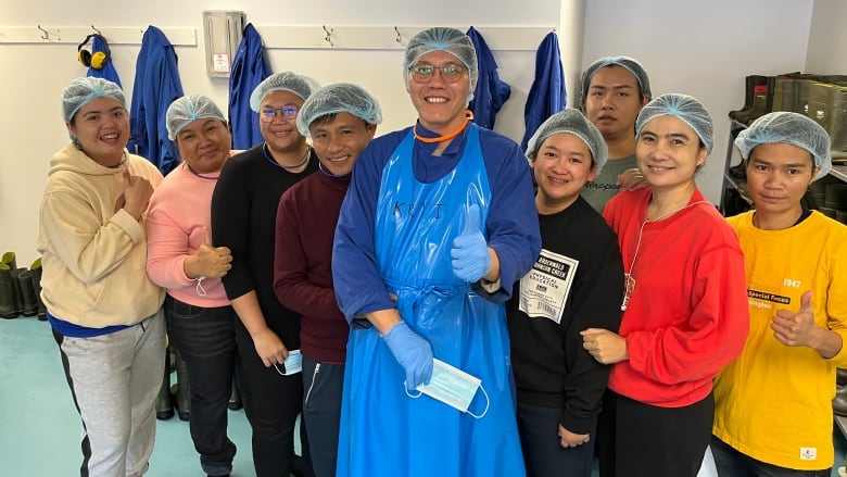 A group of workers from Thailand pose at the seafood plant in Bay de Verde.