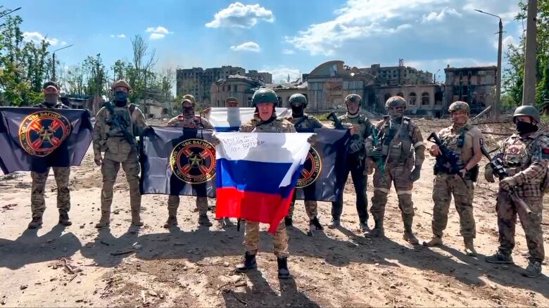 Soldiers stand carrying weapons and flags.