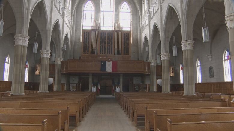 An organ sits above pews and an aisle.