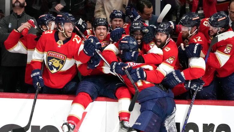 Hockey players celebrate on the bench.