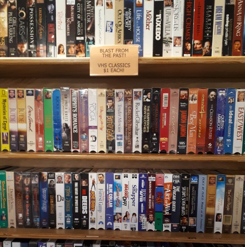 A shelf in the video store is packed with VHS tapes.