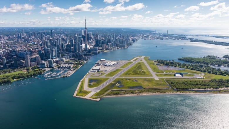 An aerial shot of an island airport with a skyline in the background.