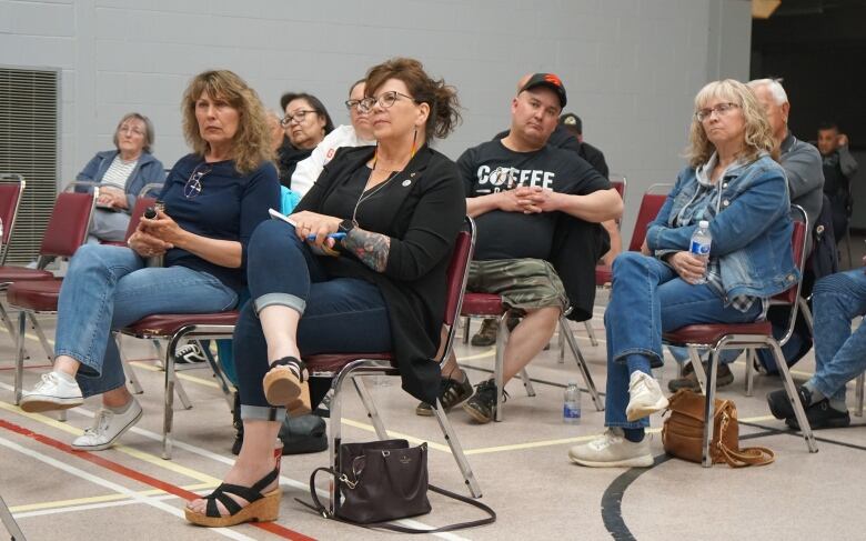 People sit in chairs in a gymnasium.