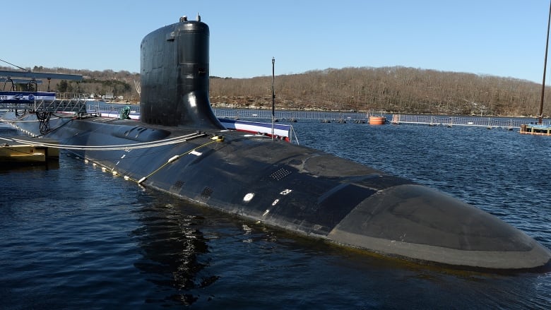 A submarine floats on the surface in harbour.