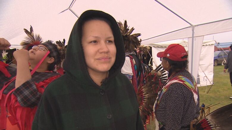 Cierra Twist is in a black hoodie with the hood up and there are people in the background of the powwow.