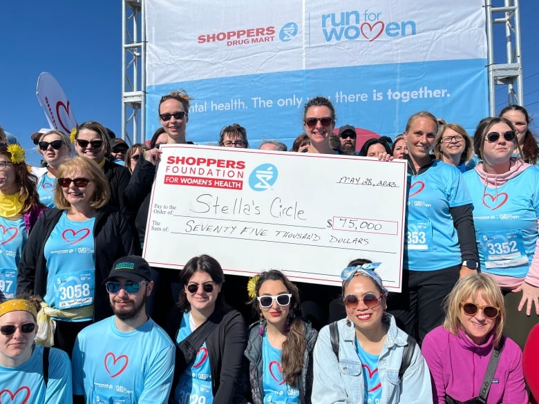 Dozens of people pose with a large novelty cheque, totaling $75,000. 