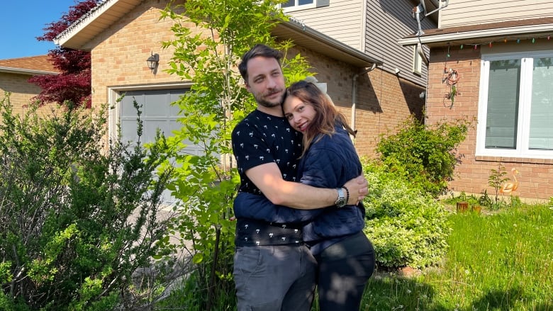 A couple hugs in front of a home on Hamilton Mountain.