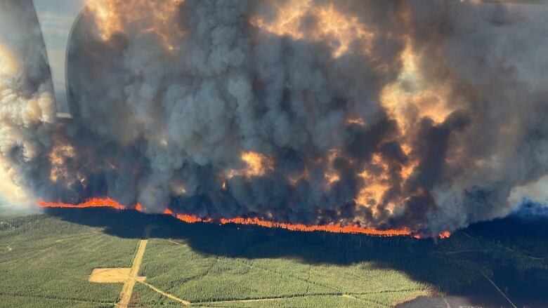 A wildfire sends up thick plumes of smoke