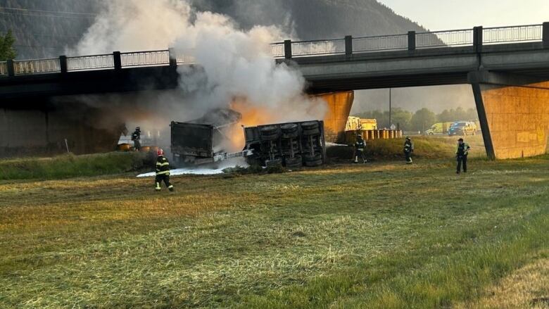 Firefighters fight a dump truck fire under an overpass