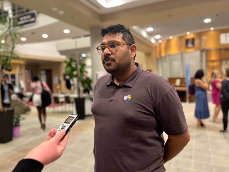 A man in brown shirt stands near a recorder