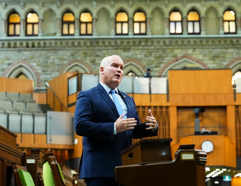 A man in a blue suit and tie speaks in the House of Commons.