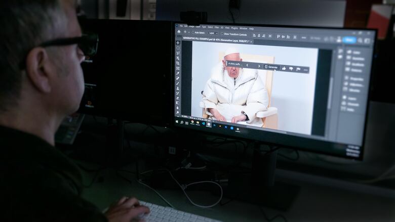 A man sits at a computer using Photoshop