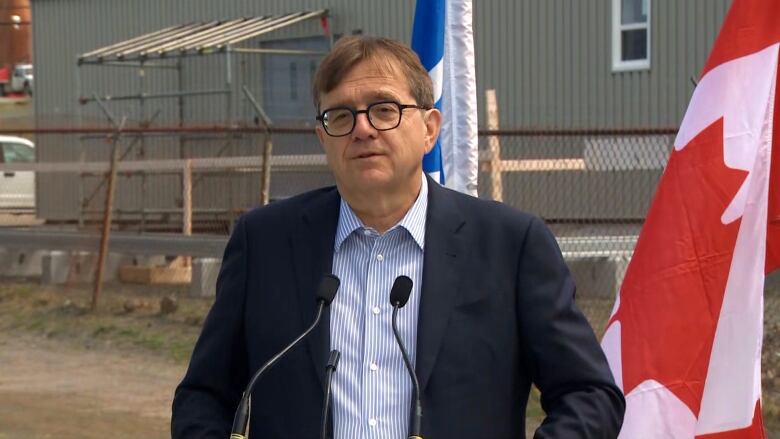 A man wearing a suit stands in the yard of a refinery.