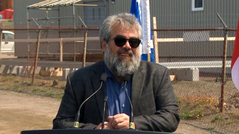 A man with a long, grey beard stands at a podium.