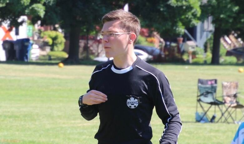 A referee dressed in all black during a youth soccer game.