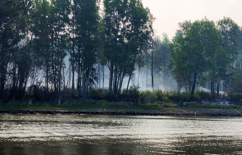 Smoke can be seen from the riverbank in Fort Chipewyan