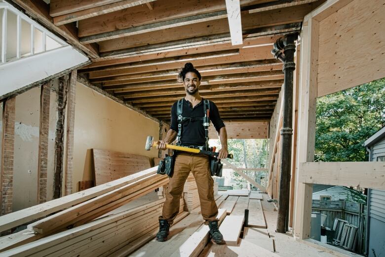 A photo of Sebastian Clovis, a builder and the host of HGTV Canada's Gut Job, posing at a building site.