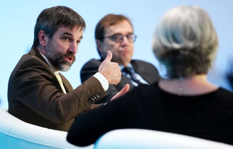 One politician gives a thumbs up with two others watch on, during a panel conversation.