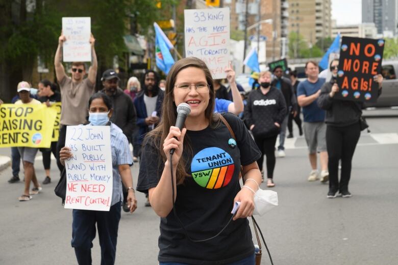 A woman holds a microphone while marching with a crowd.