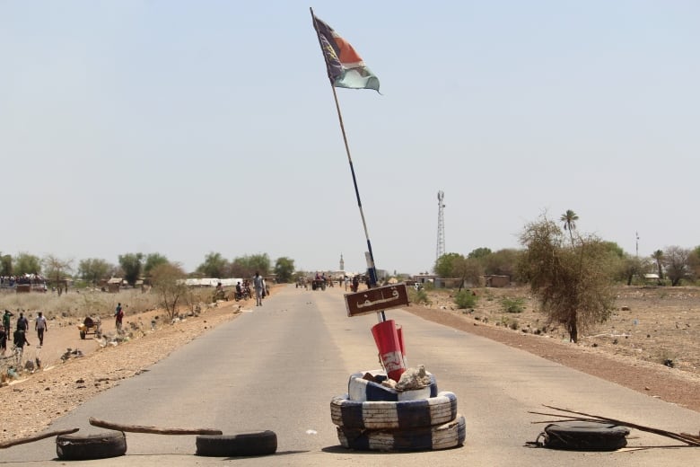 A road with tires strewn across it, one holding a flag.