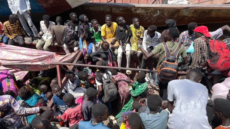 An open-top boat crammed full of people.