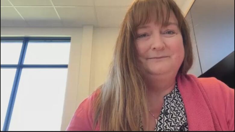 A woman smiles to the camera while on a video call.