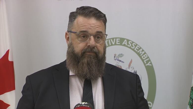 Hal Perry stands in front of a microphone in a media briefing room.