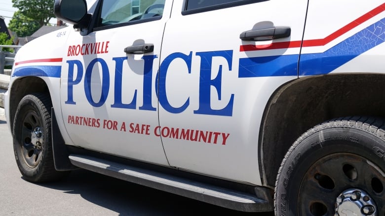 A white SUV with and red and blue stripe on its side, along with the words Brockville Police and the motto 