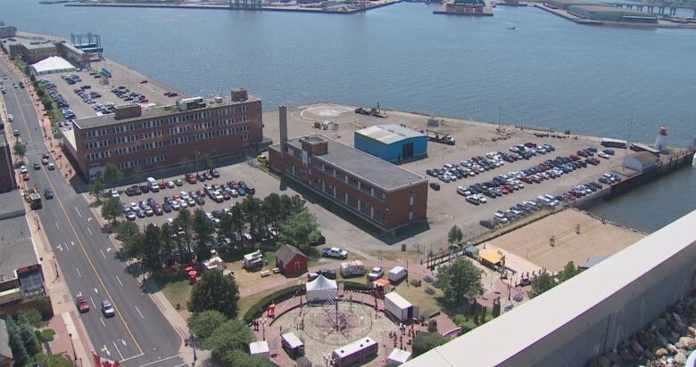 An aerial shot of a waterfront property with brick buildings and large parking areas. 