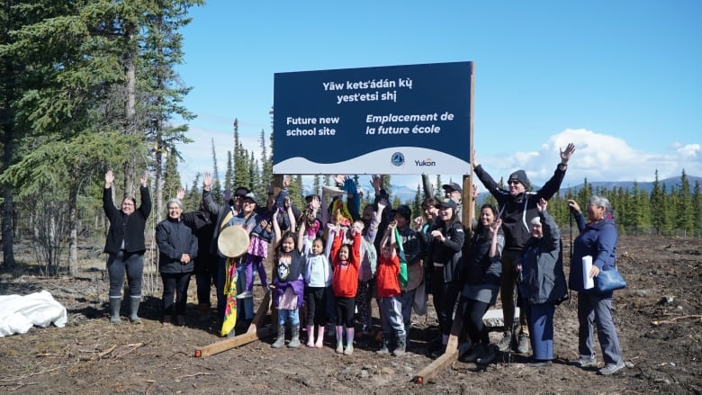 Children and adults celebrate in front of a sign. 