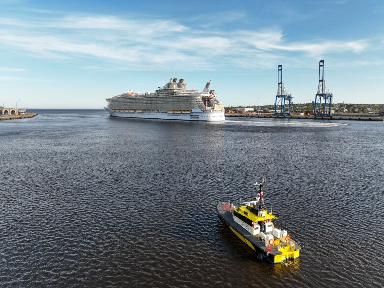 A tiny pilot boat dwarfed by a massive cruise ship