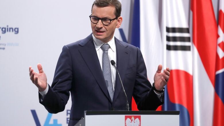 A man in glasses stands at a podium.