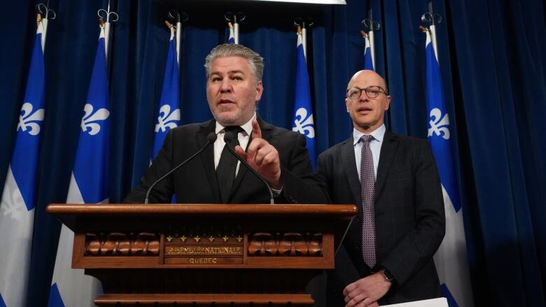 two men, one speaking at podium