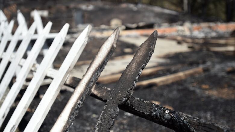 Closeup of a burned white wooden picket fence.