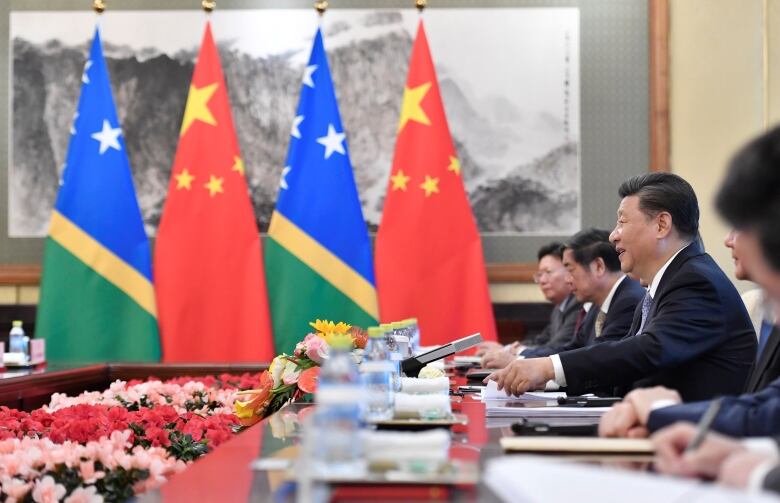 Xi Jinping at a long table, surrounded by aides