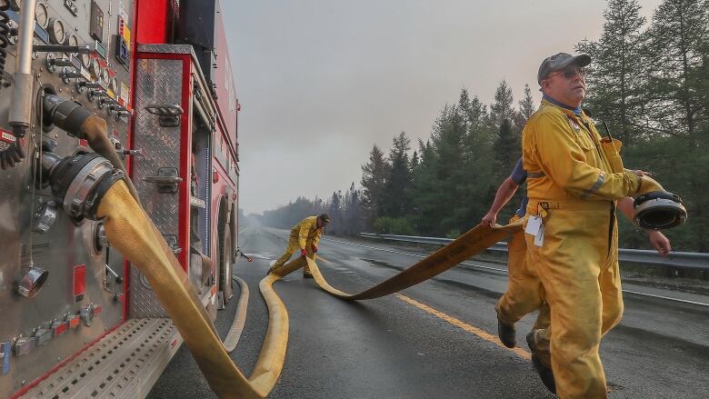 Firefighters run a hose at a wildfire scene