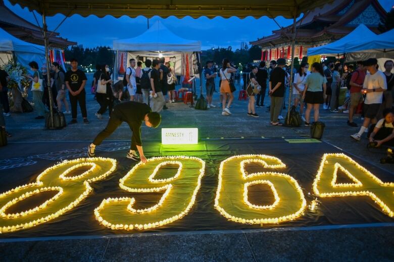 A person places a candle among others that form the numbers '8964.'