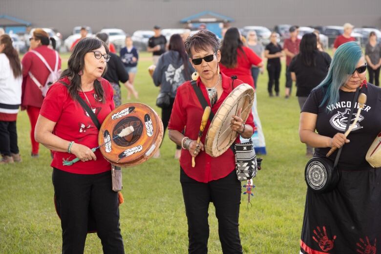 Two people beat traditional drums at a vigil.