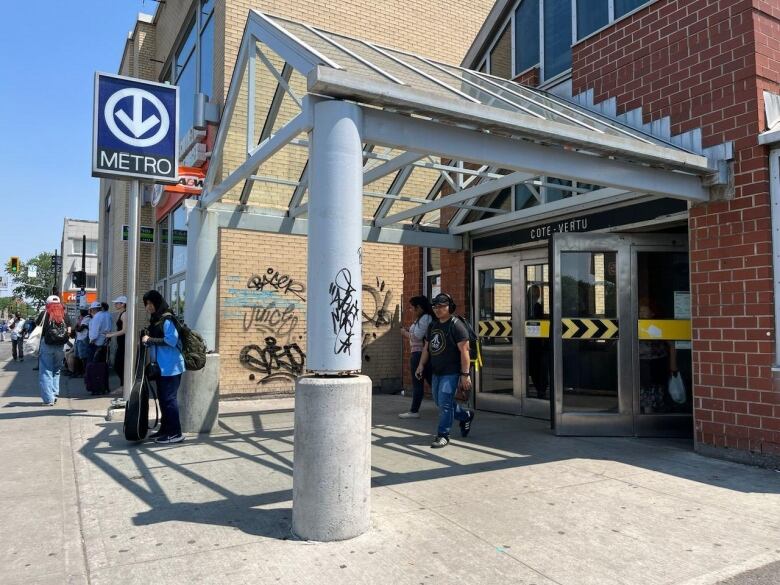 People exit and enter a metro station.