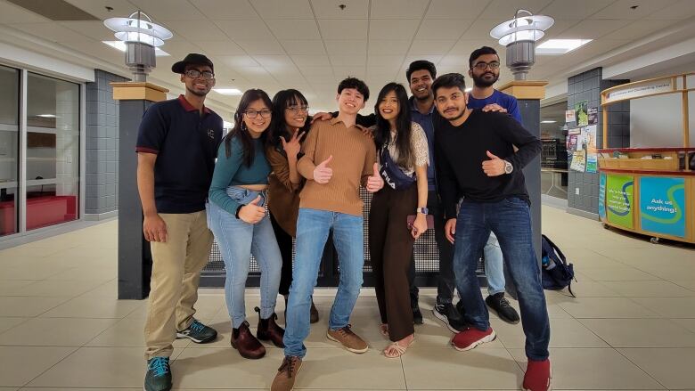 A group of people smile for the camera, some giving the thumbs up.