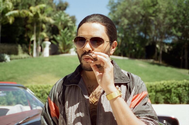 A man with slicked-back hair sticks a toothpick in his mouth.