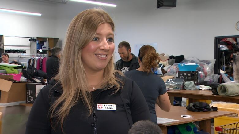 A woman with blonde hair smiles at the camera. She is wearing a black shirt and a name tag that reads, 'Lauren'