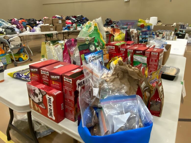 Boxes of pet supplies and other donated items are sitting on a table in a church's gymnasium. 