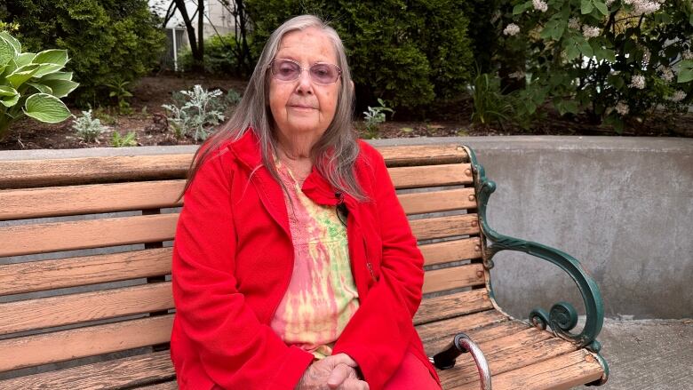 A woman on a bench smiles at the camera for a photo.