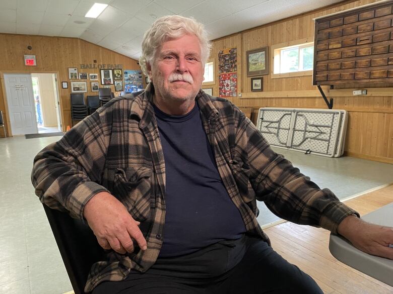 A man sits on a chair in a community centre. 