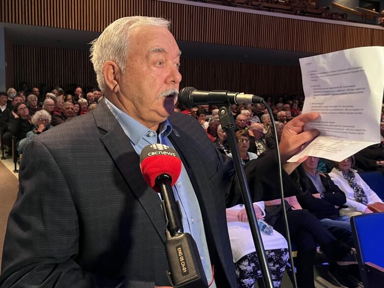 A man stands at a podium with a paper in his hand. 