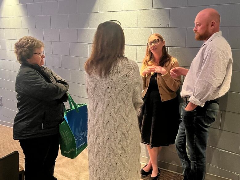 Four people speak in a circle following a public meeting. 