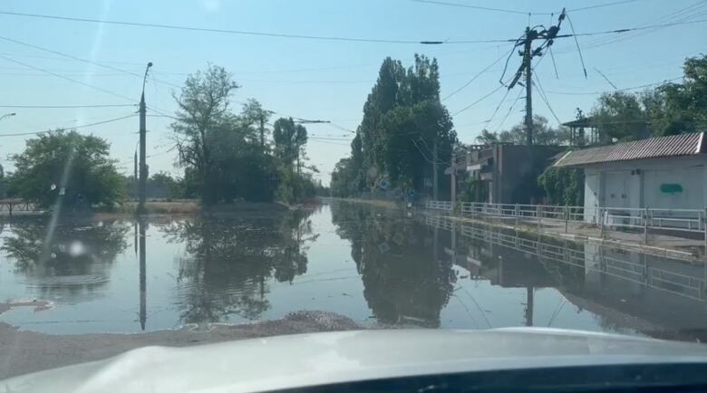 A view from the dashboard of a vehicle shows a flooded street.