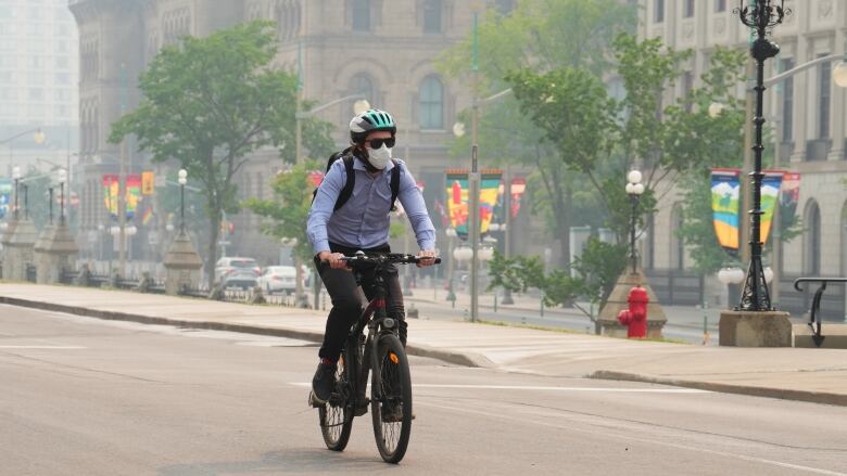 A cyclist rides his bike while wearing a mask due to the poor air quality in the aftermath of wildfires in Ontario and Quebec.