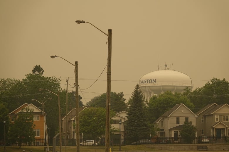 Brown smoke over a city street and water tower.